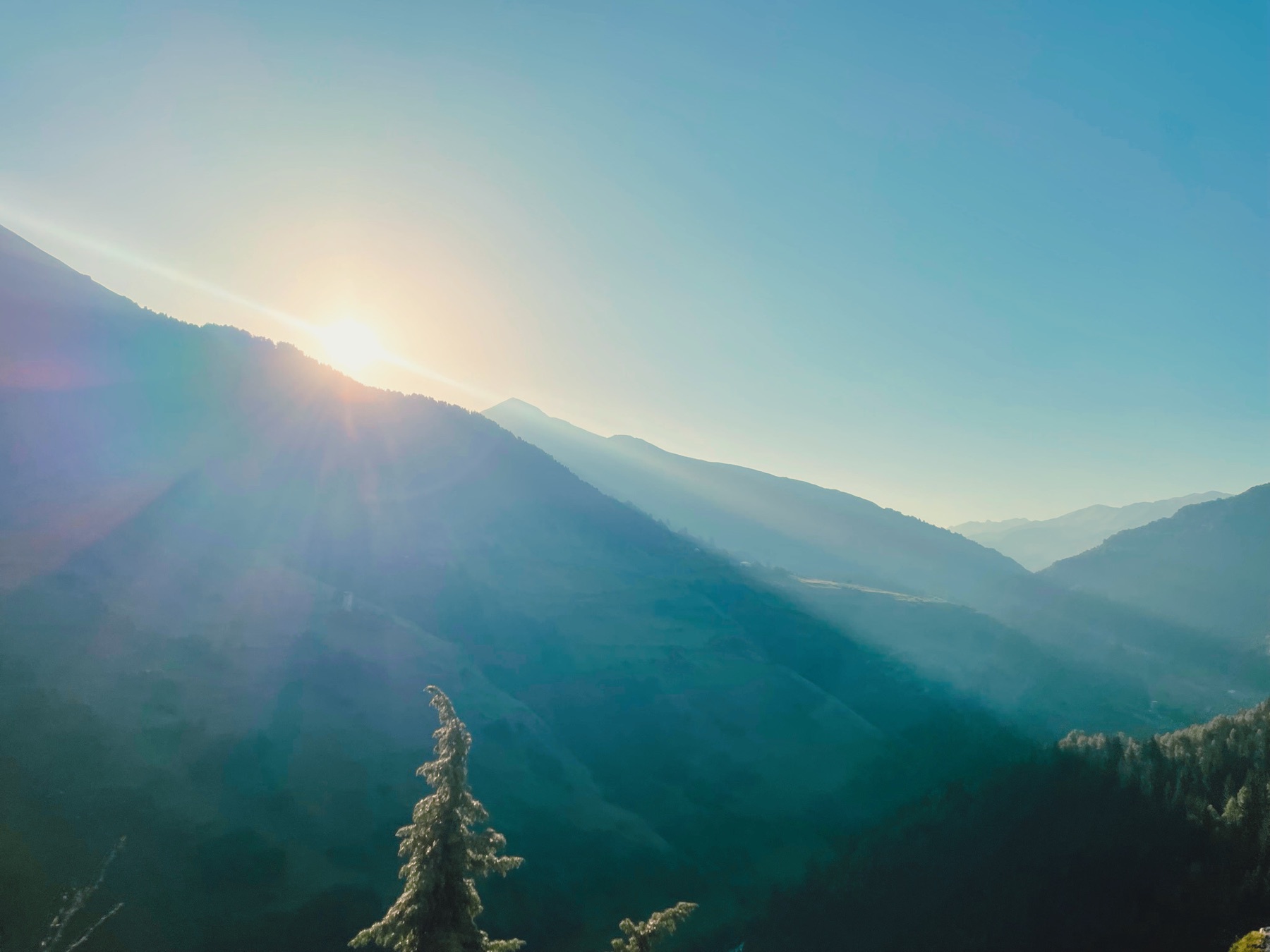 Sonnenstrahlen über einem Bergtal am Morgen